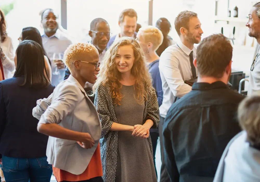 Diverse group of people socializing at a casual gathering. Men and women of various ethnicities engaged in conversation, enjoying a lively social event. Diverse people mingle at a social event.